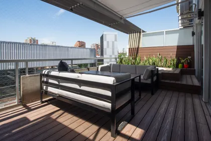 Terraza moderna con deck de madera y vista urbana — proyecto Depto Arribeños, por Ayelen Mayer Arquitectura, en Buenos Aires